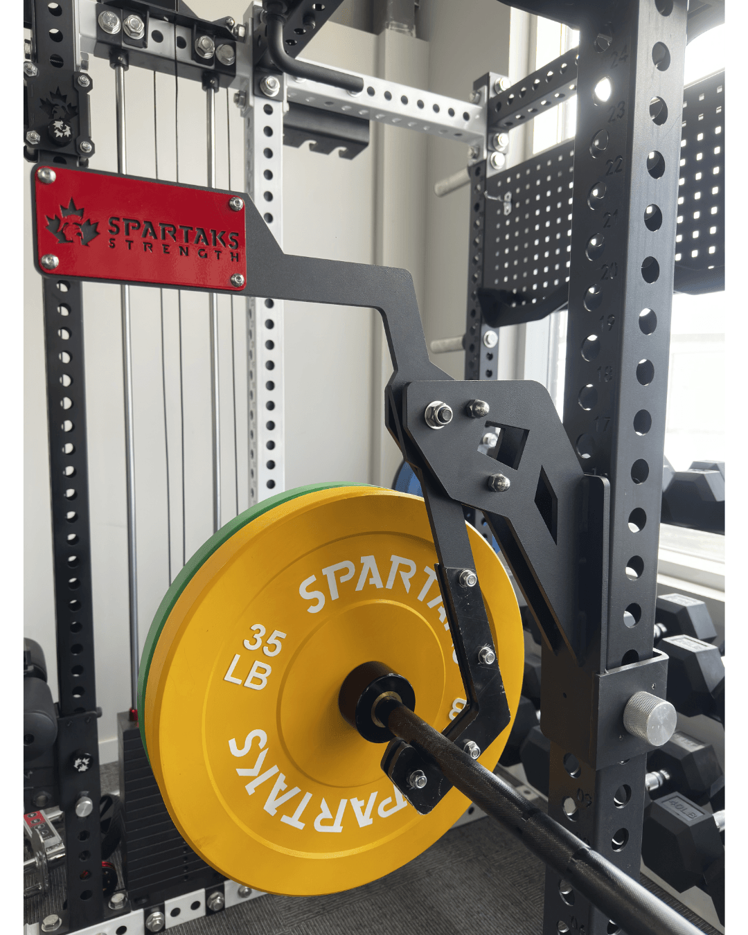 Spartaks Strength Adjustable Monolift Rack Attachment with 35 LB weight plate on power rack in home gym.