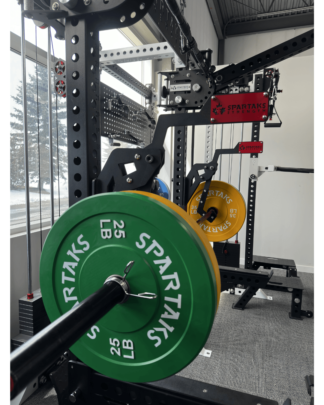 Spartaks Strength Adjustable Monolift Rack Attachment with weights in a home gym setting.