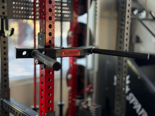 Spartaks Strength Y-Shape One Piece Dip Station (Adjustable Width) attached to a squat rack for strength training.