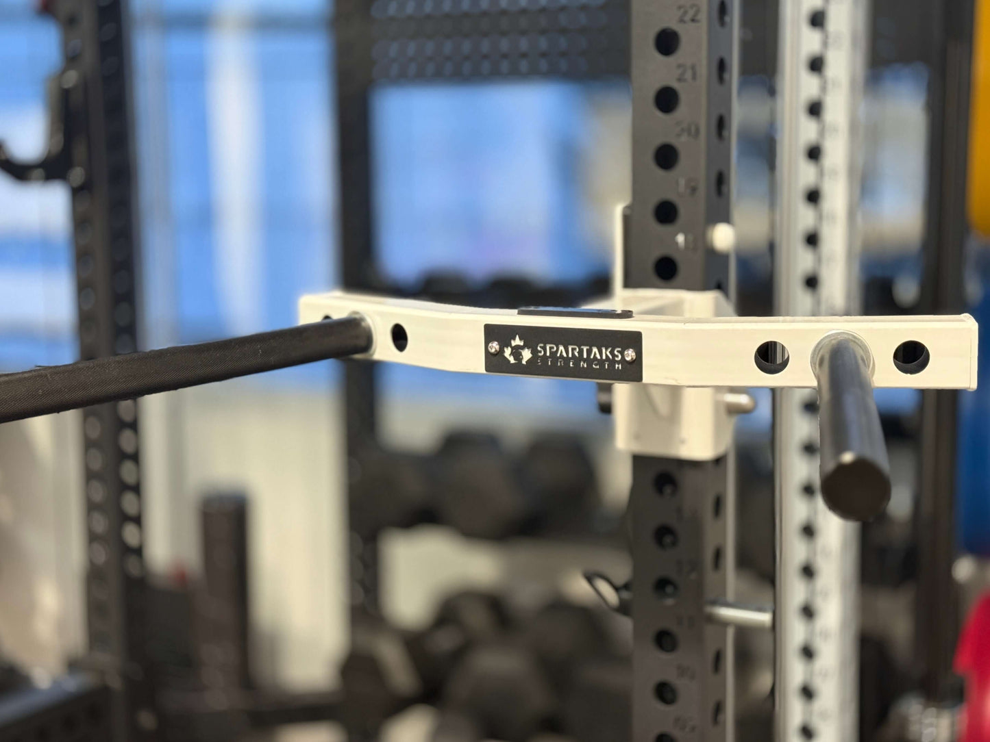 Close-up of Spartaks Strength Y-Shape One Piece Dip Station (Adjustable Width) with weight bar attachment in gym.